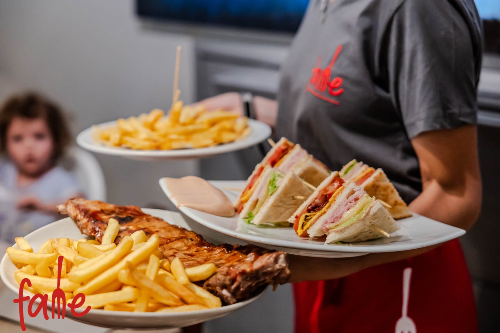 Ein Kellner bringt Gerichte und Pommes zum Tisch